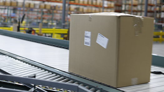 A container being intelligently routed on automated conveyor, distribution center in the background.