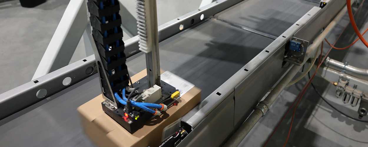 Print and apply label applicator adding label to a carton on a belt conveyor