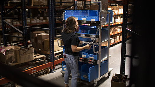 3PL fulfillment center employee batch picking orders with pick-to-light smart cart.