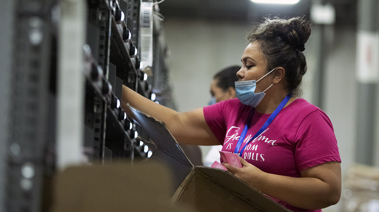 A distribution center employee using a put wall to sort items for ecommerce orders.